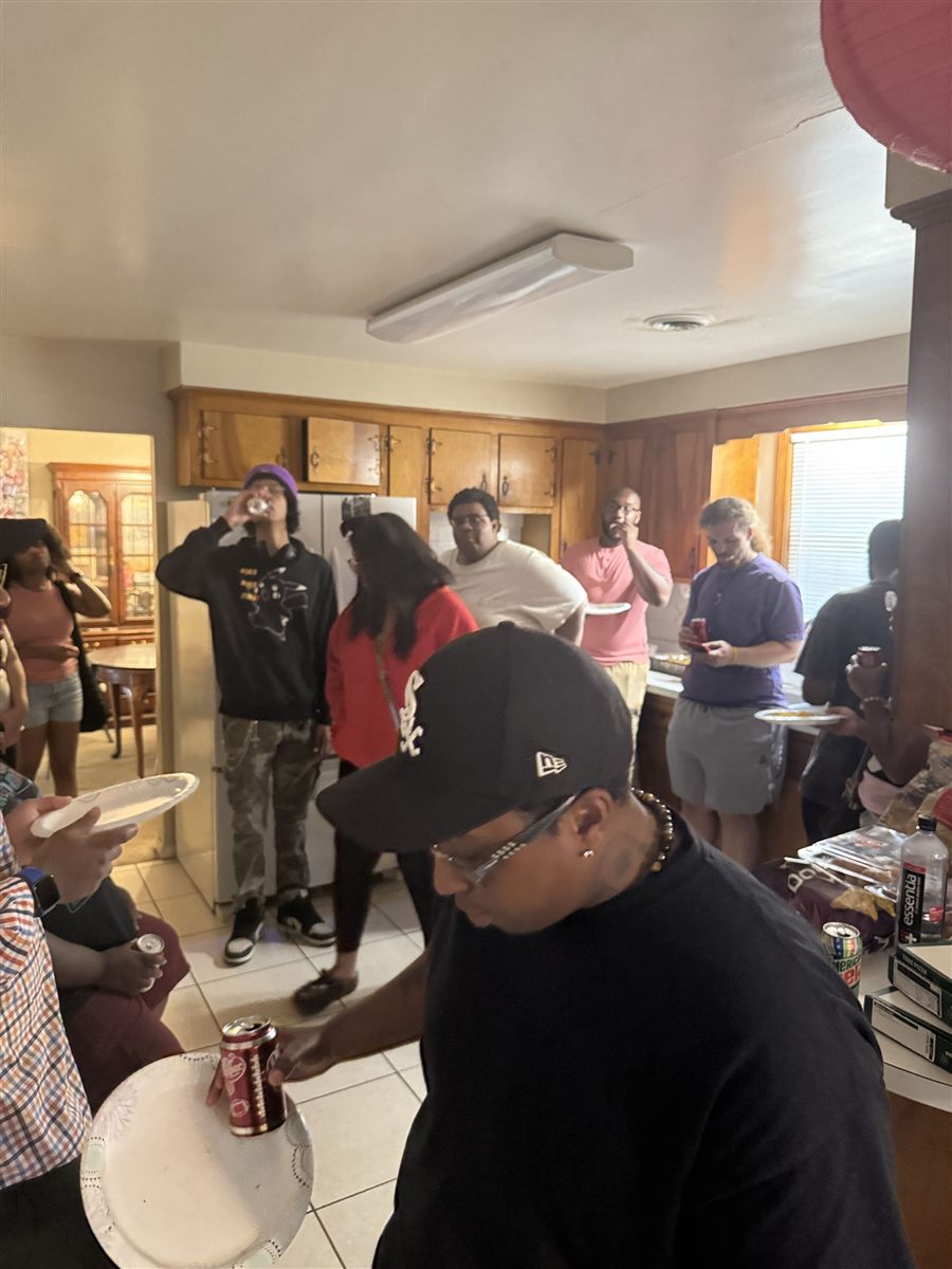 Club members sharing food and conversation in a kitchen during a meetup